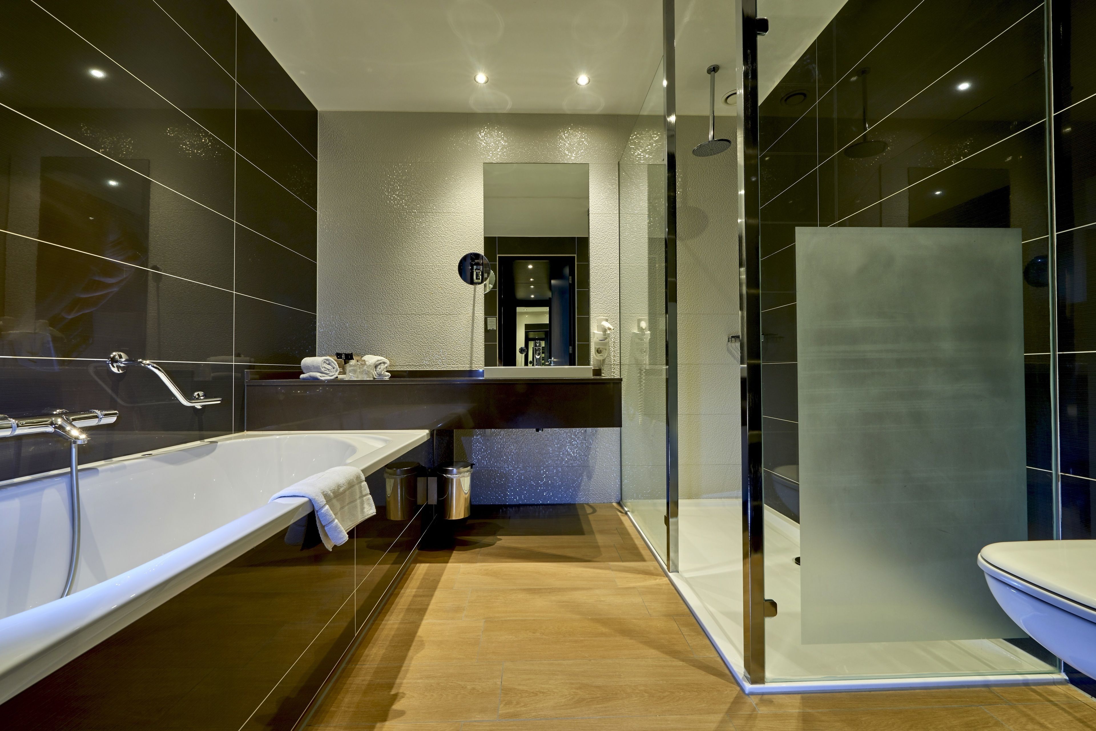 A modern bathroom with a large bathtub, a glass-enclosed shower, and a separate toilet area.