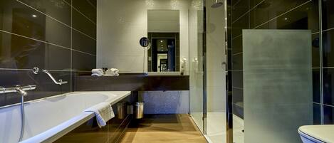 Un baño moderno con una bañera grande, una ducha con cerramiento de vidrio y un área separada para el inodoro.