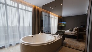 Une salle de bain moderne avec une grande baignoire sur pieds, un miroir et un téléviseur fixé au mur.