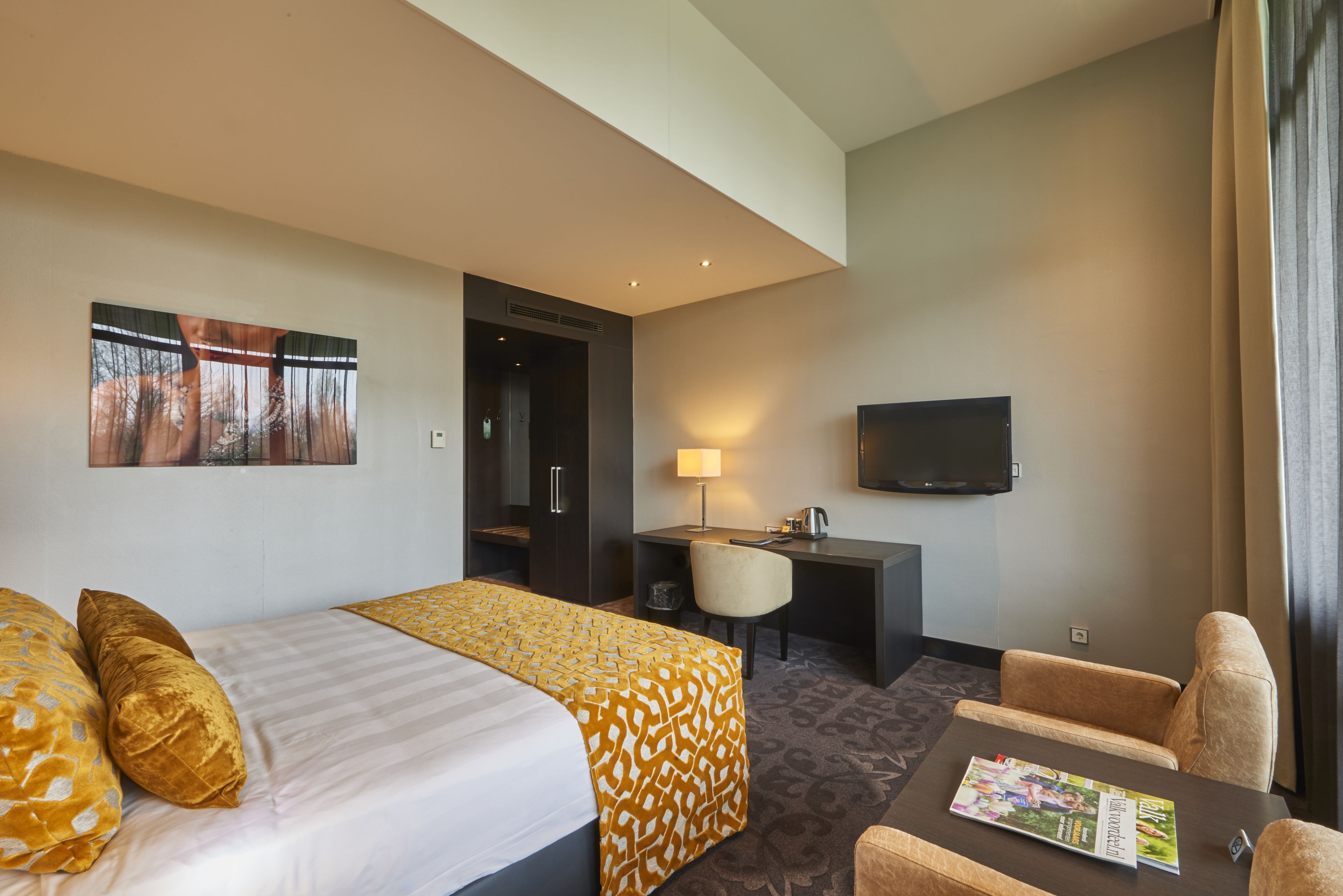 A hotel room with a bed, a desk, a chair, and a TV.