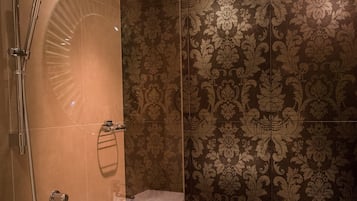 A bathroom with a shower, a sink, and patterned tiles.