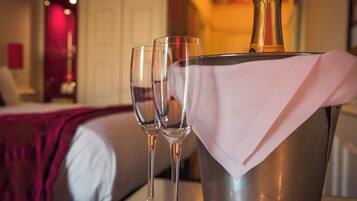 Une chambre d’hôtel avec un lit, une table de chevet et une bouteille de champagne dans un seau à glace.