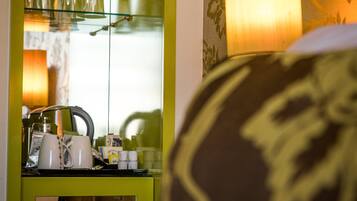 A room with a green minibar, a lamp, and a bed with a patterned pillow.