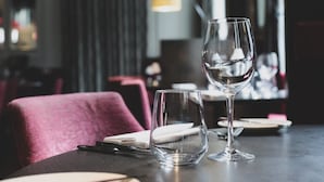 Una mesa de restaurante preparada con una copa de vino, un vaso de agua y cubiertos.