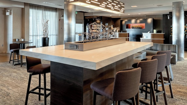 A modern bar area with a marble countertop, bar stools, and a decorative centerpiece. - Courtyard by Marriott York (York)