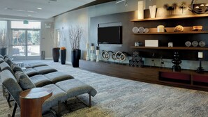 A modern hotel lobby with a seating area, a large TV, and decorative shelves. - Courtyard by Marriott York (York)