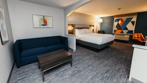 Ein Hotelzimmer mit einem blauen Sofa, einem Bett, einem kleinen Tisch und einem Schreibtisch.