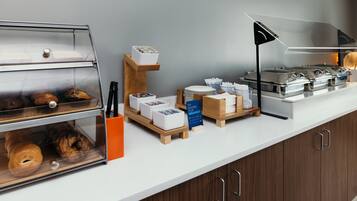 A breakfast buffet setup with various food items and utensils.