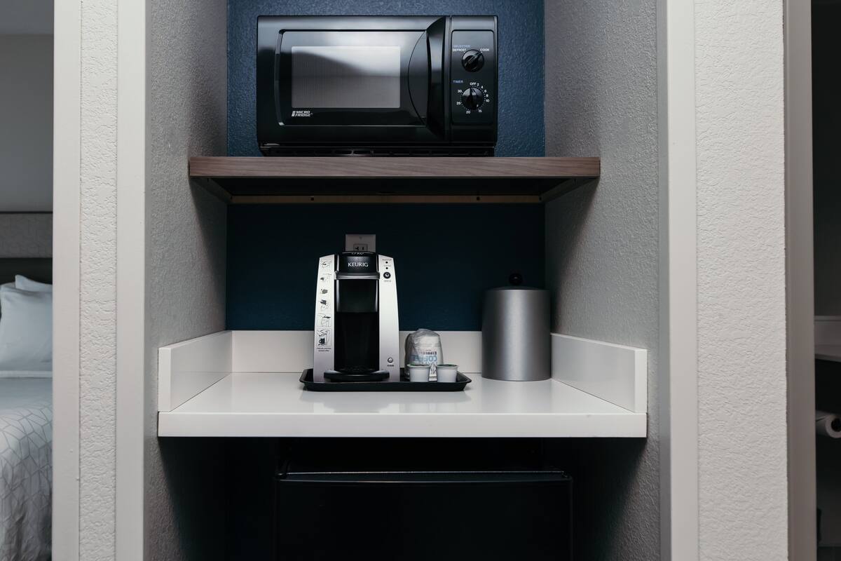 A kitchenette with a microwave, coffee maker, and a small refrigerator.