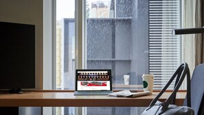 A laptop on a desk with a coffee cup and a handbag, near a window with a view of buildings. - Daiwa Roynet Hotel Nagoya Shinkansenguchi (Nagoya)
