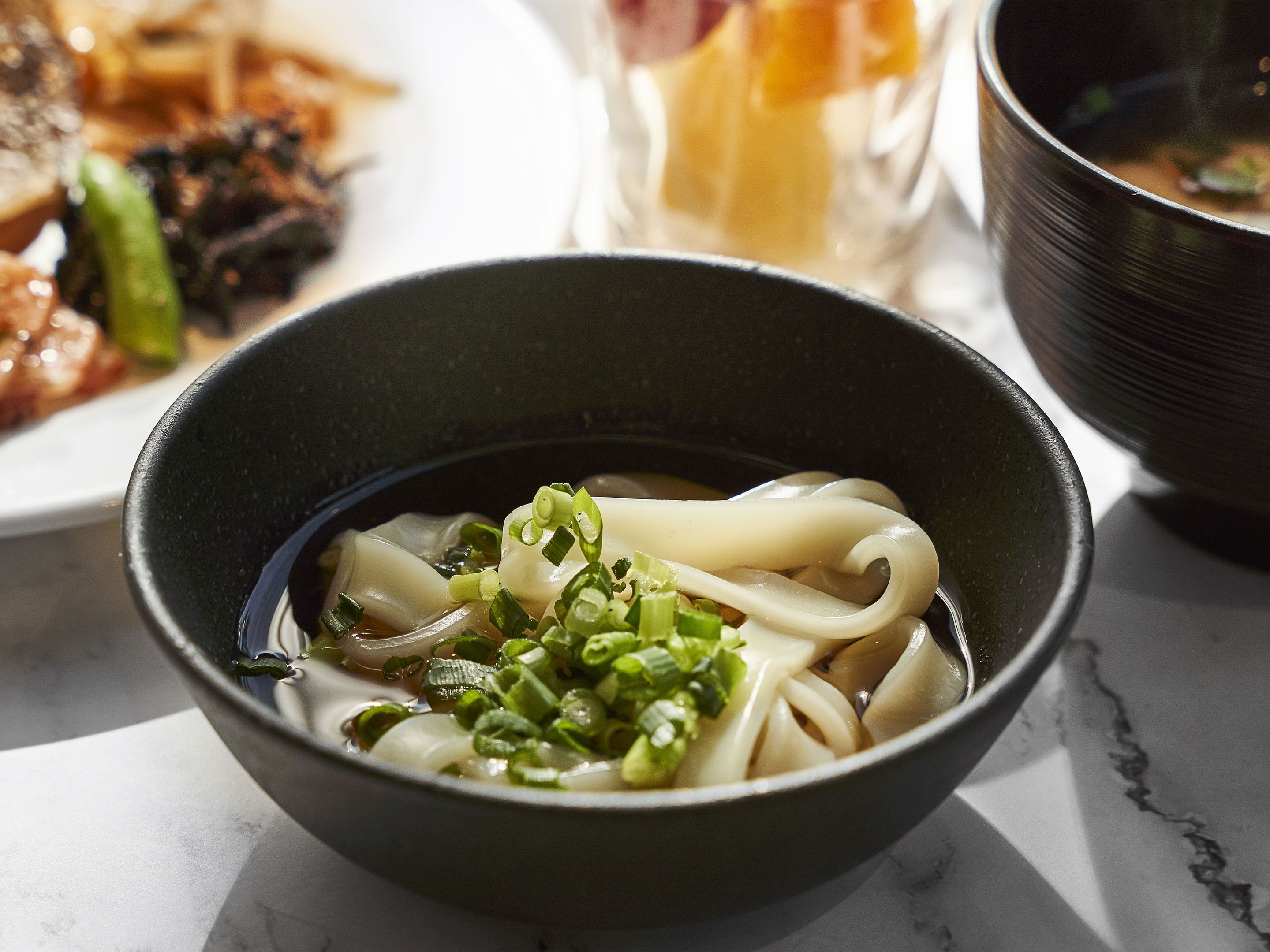 A bowl of ramen with green onions, noodles, and broth.