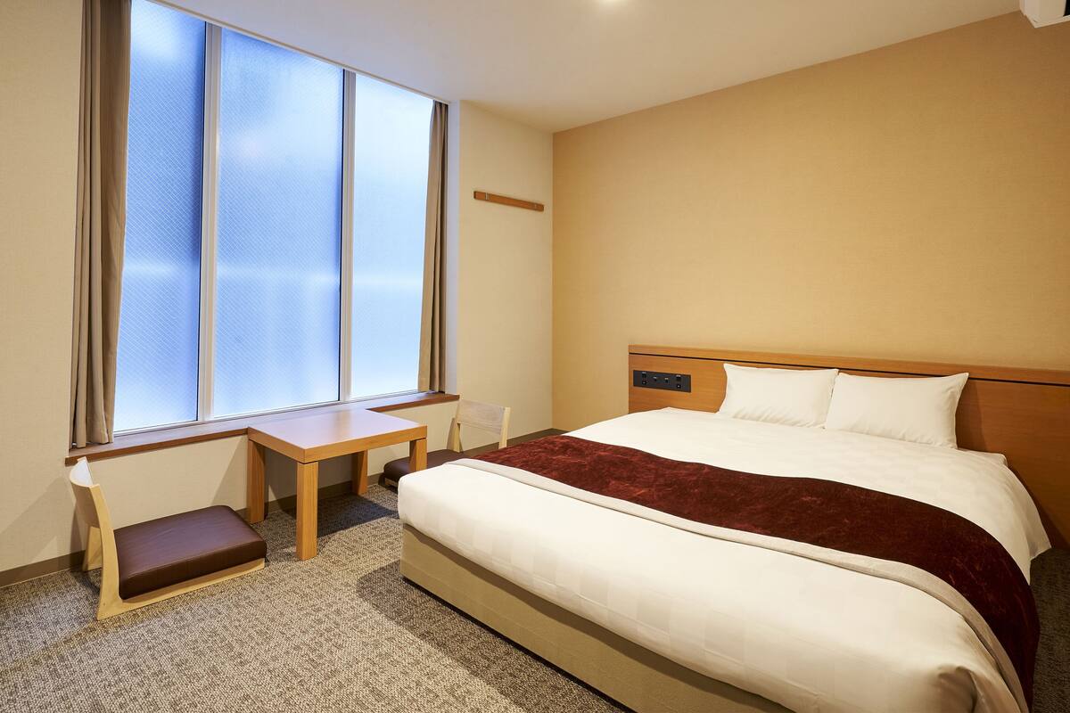 A hotel room with a large bed, a desk, and a chair.