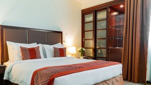 Un grand lit avec une tête de lit en bois, une table de chevet avec une lampe et une armoire aux portes en verre.