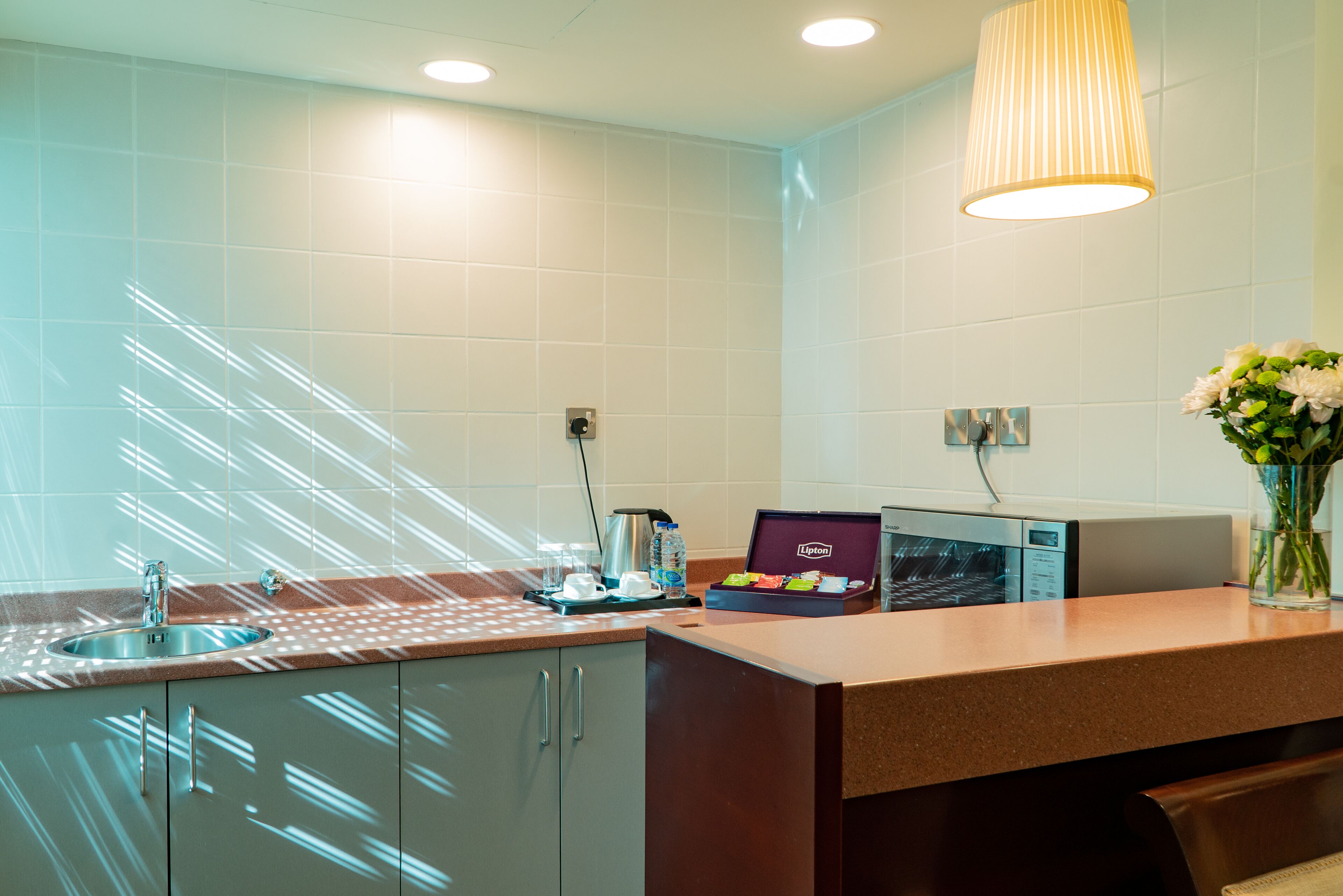 A modern kitchen with a sink, countertop, and a box of Lipton tea.
