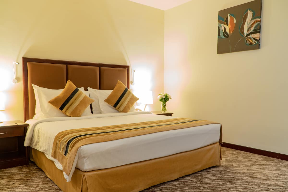 Een hotelkamer met een groot bed, een nachtkastje, een lamp en een aan de muur hangend schilderij.