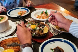 Una mesa de comedor con diversos platos, incluyendo una sartén con comida, platos con alimentos y un bol.