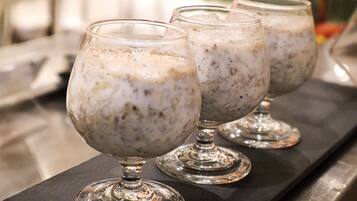 Three glasses of a creamy beverage with a grainy texture, placed on a dark surface.