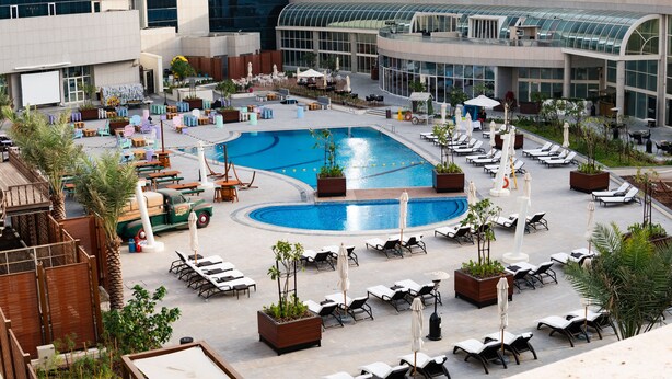 Un espace piscine aménagé sur le toit, avec des chaises longues, une piscine et un restaurant doté d’une terrasse.