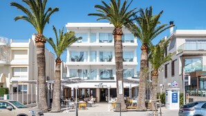 A hotel with a modern facade, outdoor seating area, and palm trees. -  Hotel Cabot Romantic - Adults Only (Pollenca)
