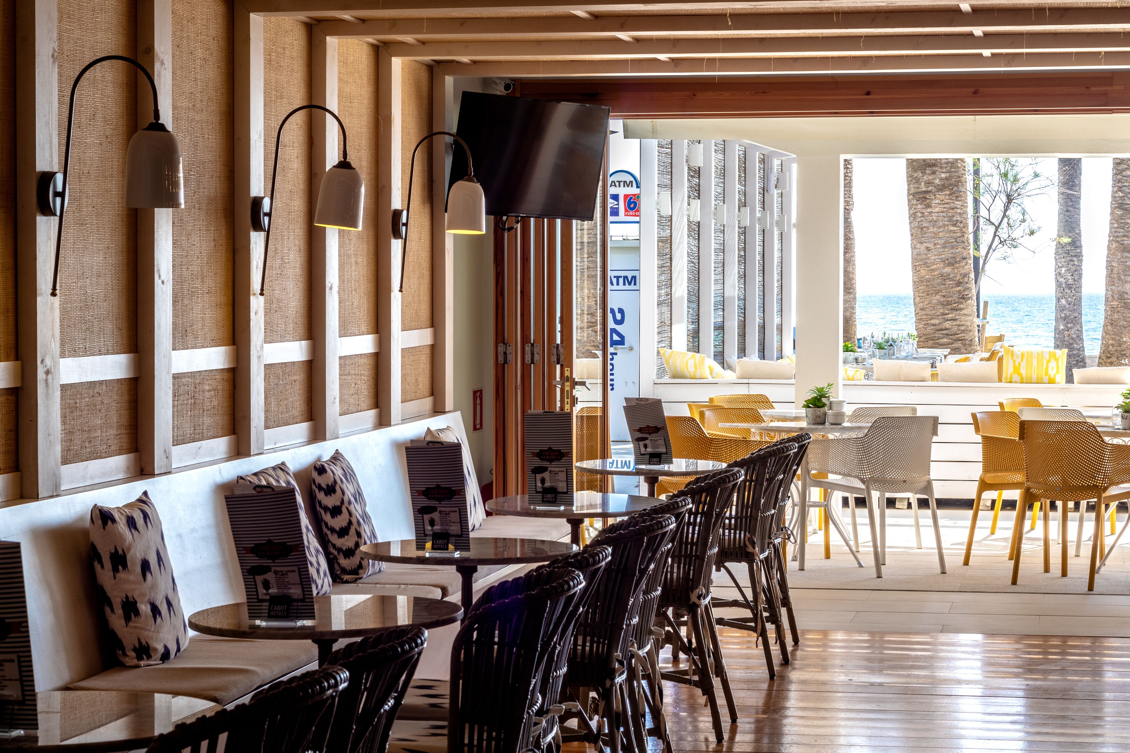 Een restaurant met houten wanden, zwart-witte stoelen en uitzicht op zee.