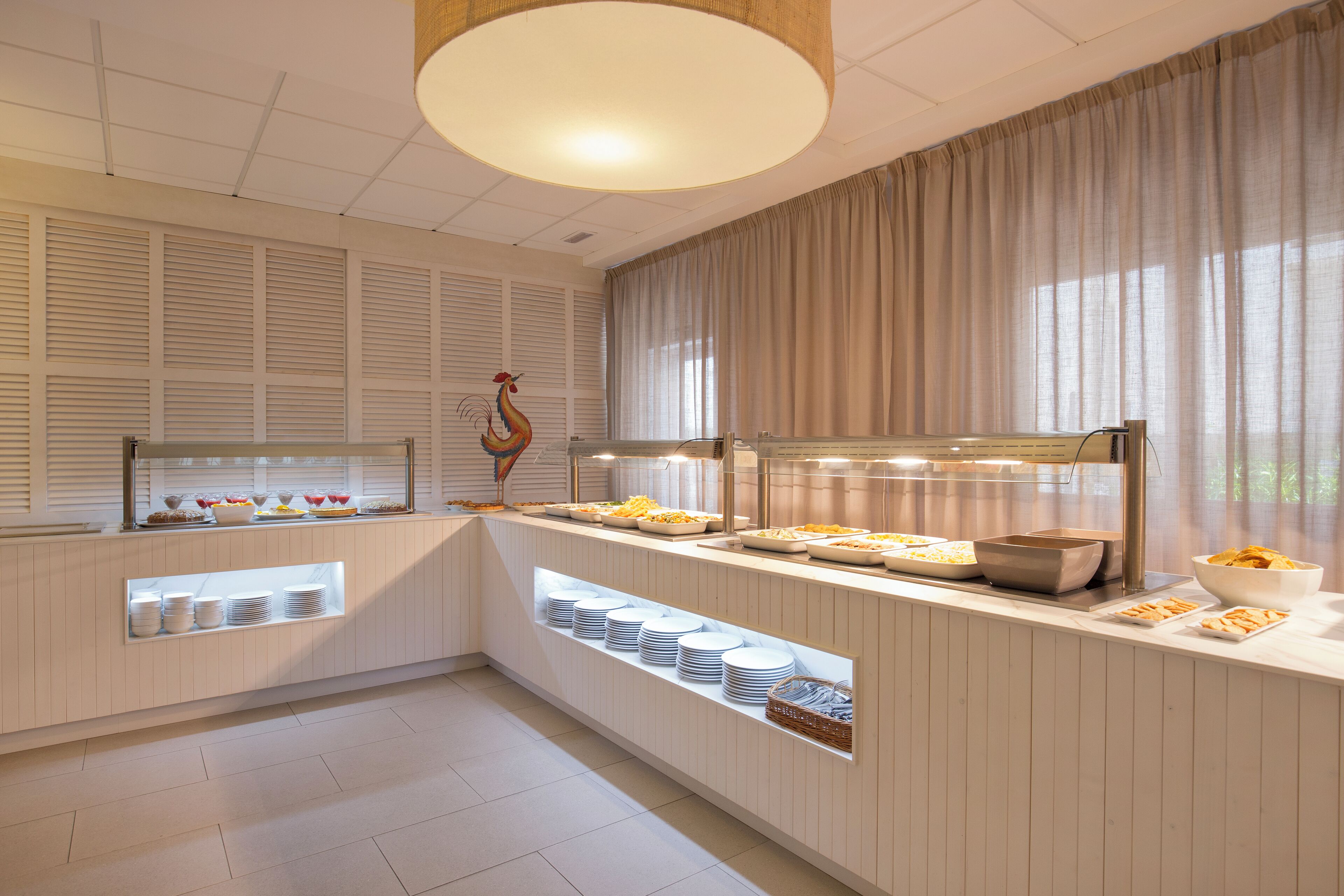 Un espace buffet proposant une variété de plats et agrémenté d’un coq décoratif.