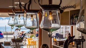 A bar with hanging glass lamps, a bottle of champagne, and a view of the sea. -  Hotel Cabot Romantic - Adults Only (Pollenca)