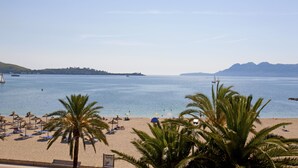 A beach with palm trees, umbrellas, and lounge chairs. -  Hotel Cabot Romantic - Adults Only (Pollenca)