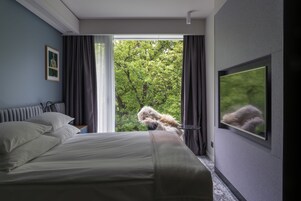 Quarto com cama grande, televisão e janela com cortinas.