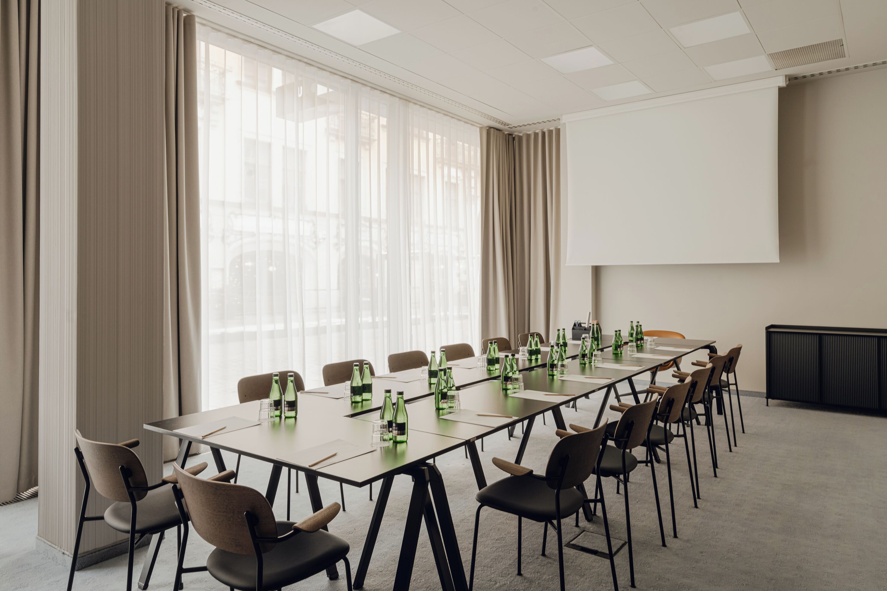 A conference room with a long table, chairs, and a projector screen.