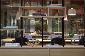 A modern office space with a wooden desk, books, a decorative vase, and a potted plant. - PURO Wrocław Stare Miasto (Wroclaw)