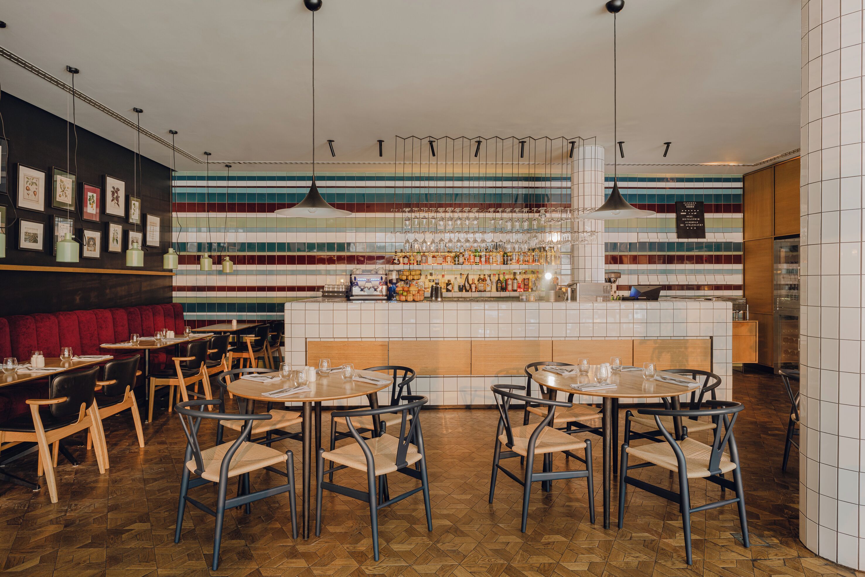 A restaurant interior with striped tile walls, wooden tables, and chairs.