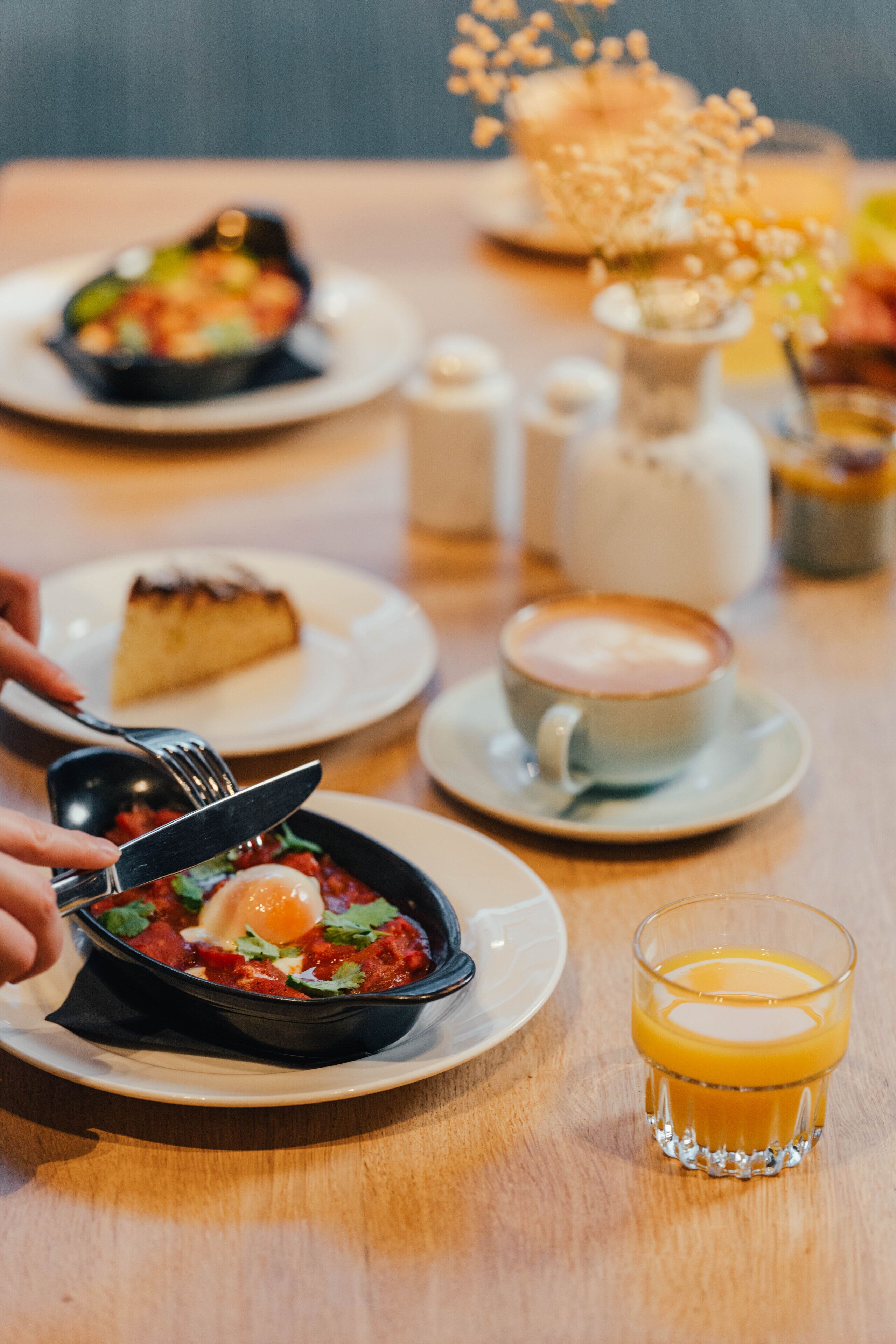 A breakfast setting with a plate of food, a cup of coffee, and a glass of orange juice on a wooden table.