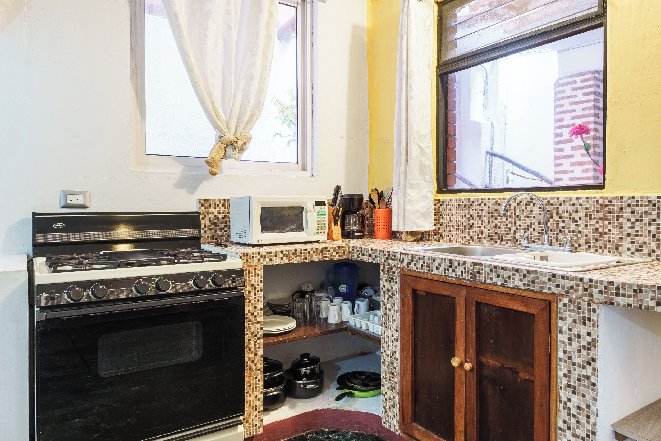 A compact kitchen with a stove, microwave, and sink.