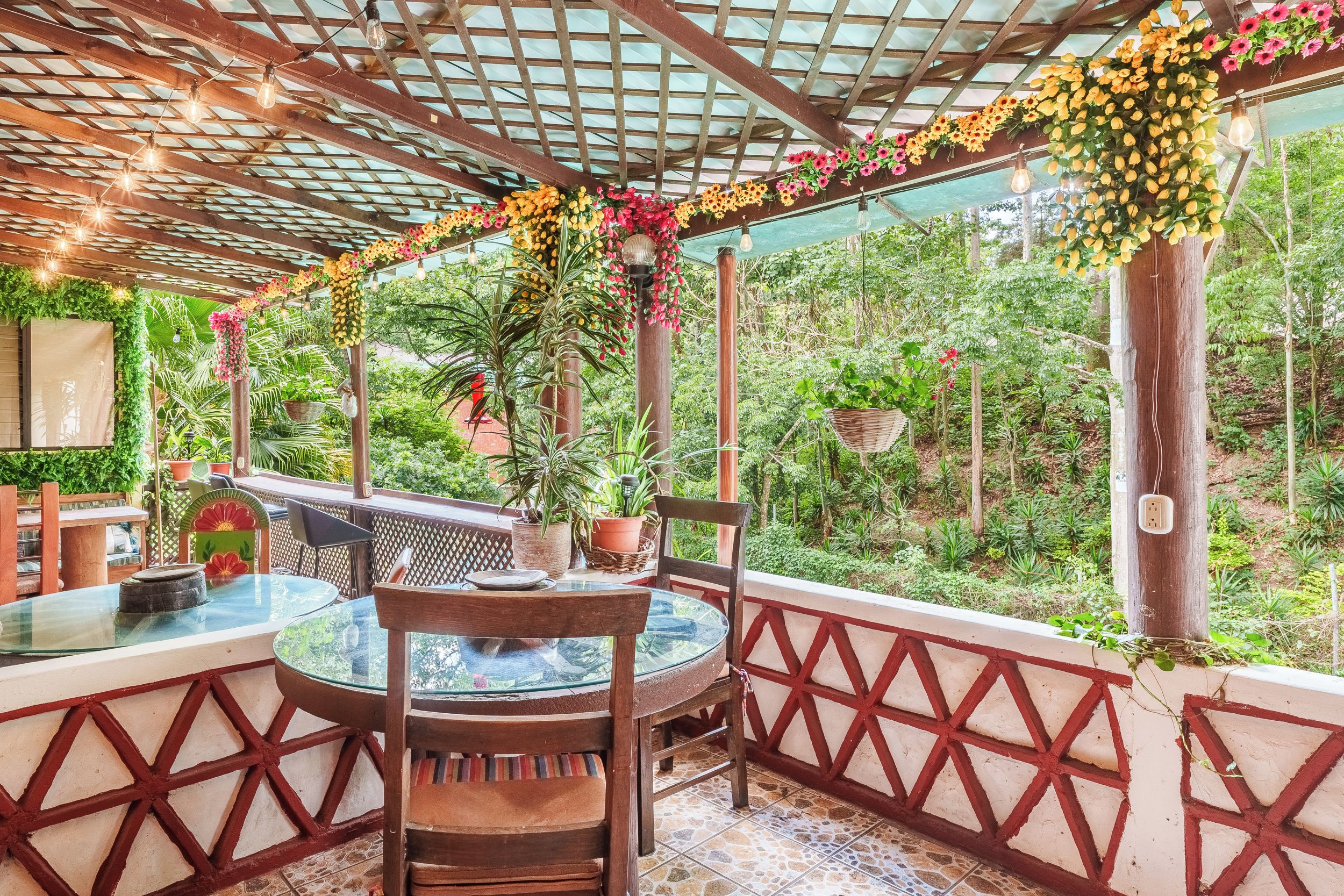 An outdoor patio with a round table and chairs, surrounded by a wooden fence and potted plants.