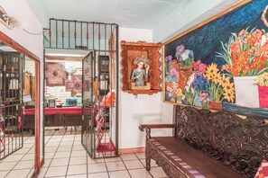A room with a wooden bench, a wall-mounted painting of flowers, and a small shrine with a statue. - Eco Suites Uxlabil Guatemala City (Guatemala City)
