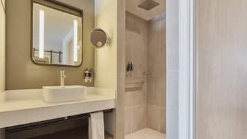 Un baño moderno con un lavabo blanco, un espejo grande y una zona de ducha.