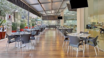 En restaurant med udendørs siddepladser, borde, stole og plantekasser.