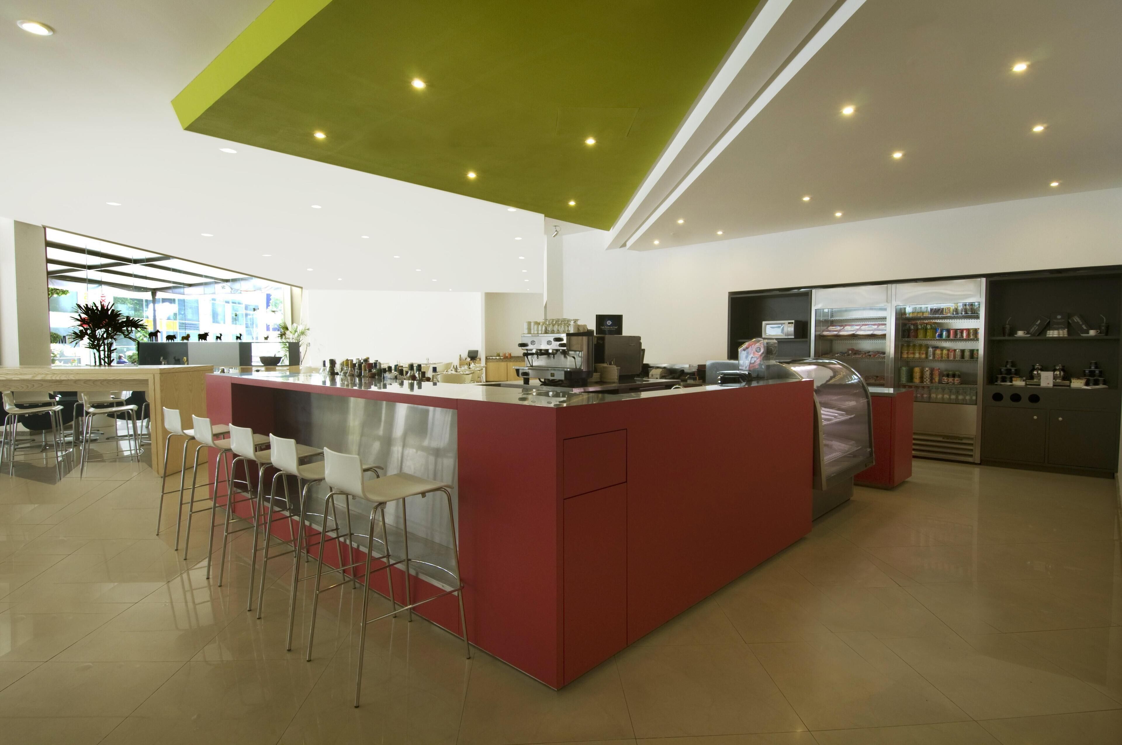 A modern kitchen with a red island, bar stools, and various appliances.