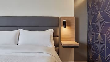 Quarto moderno com uma cama, uma mesinha de cabeceira e uma parede com padrões geométricos.