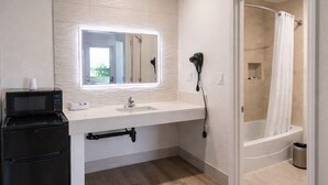 A modern bathroom with a built-in sink, a hairdryer, a shower, and a microwave. - Motel Moonlight (Anaheim)