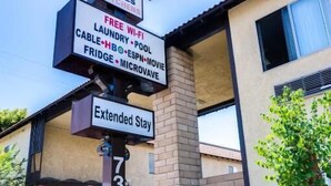 A motel sign with amenities including low weekly rates, free Wi-Fi, laundry, pool, cable, HBO, ESPN, movie, fridge, and microwave. - Motel Moonlight (Anaheim)