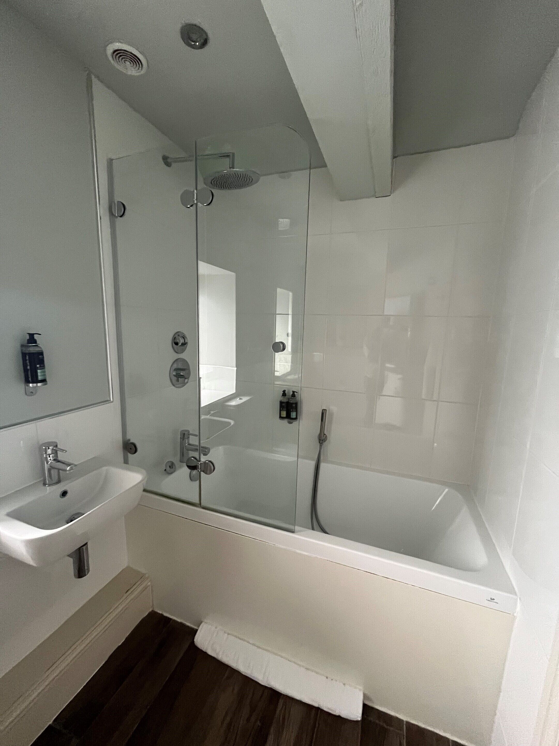 A modern bathroom with a glass-enclosed shower, a white sink, and a bathtub.