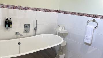 A modern bathroom with a freestanding bathtub, a towel rack, and a small shelf with toiletries.