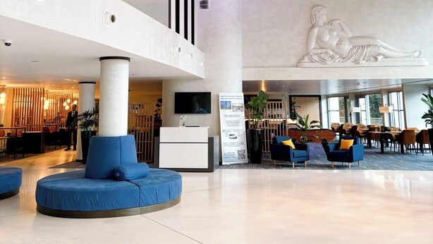 Eine moderne Hotelhalle mit Empfangstresen, Sitzbereichen und einer einzigartigen Deckeninstallation.