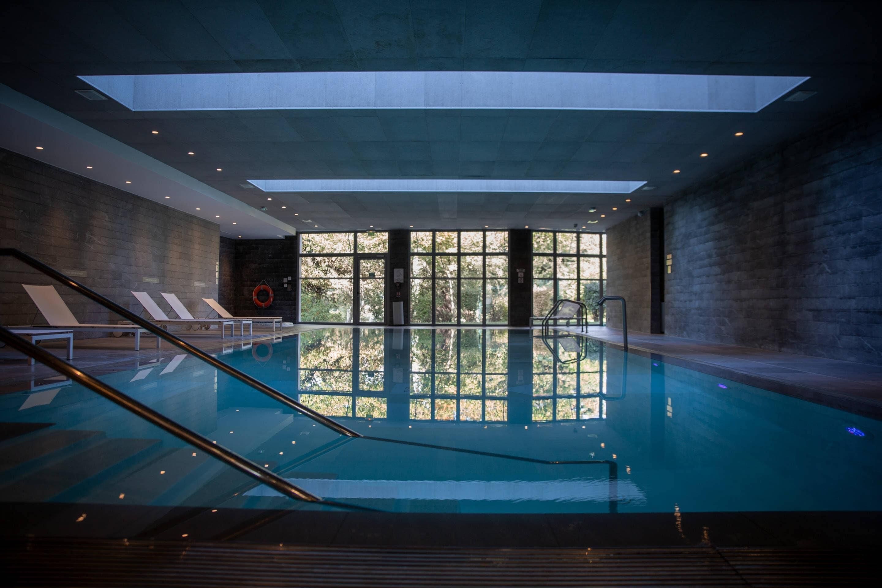 Una piscina techada, sillones reclinables de piscina