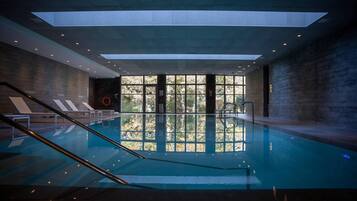 Una piscina techada, sillones reclinables de piscina