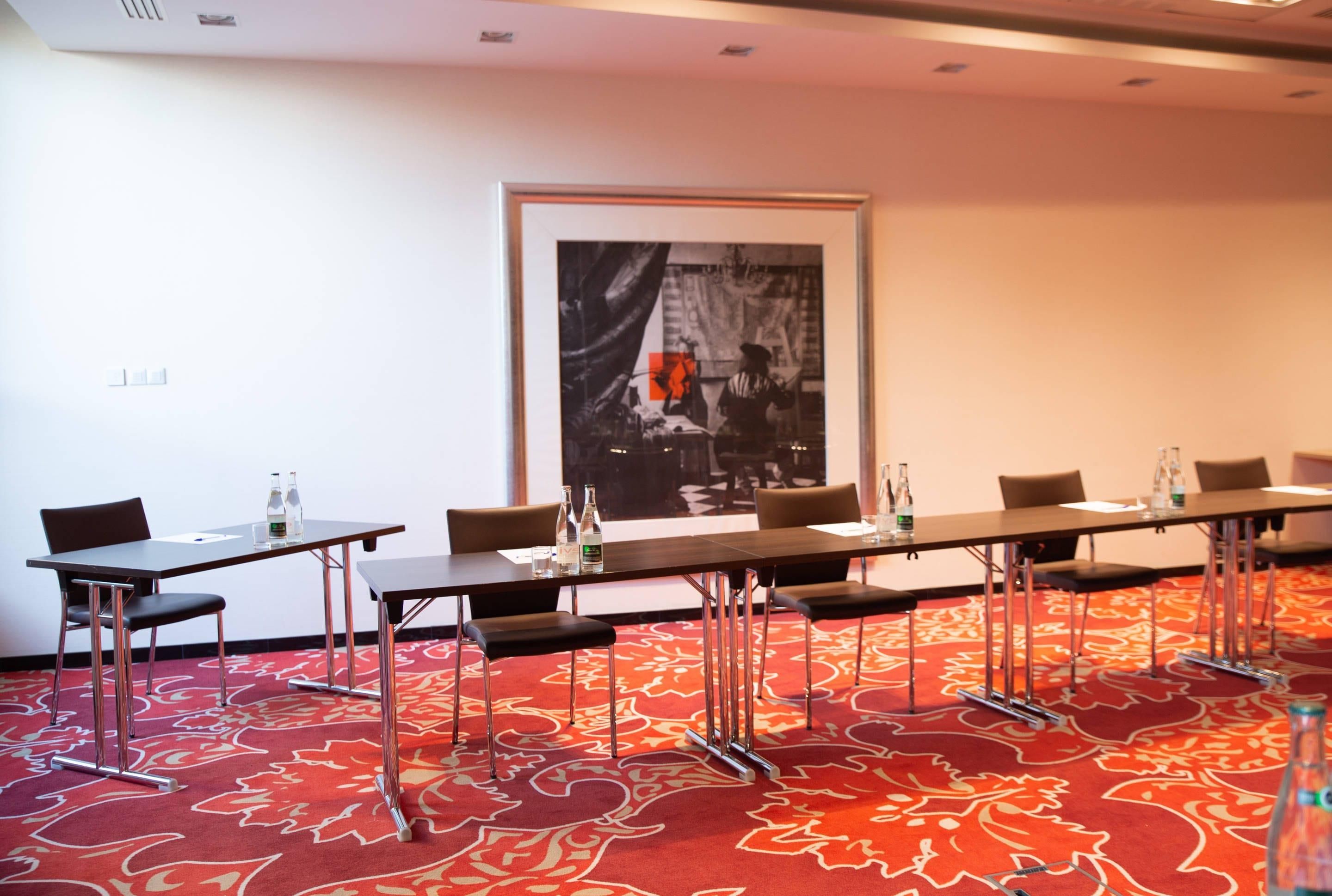 Une salle de conférence avec une longue table, des chaises et un grand tableau encadré au mur.