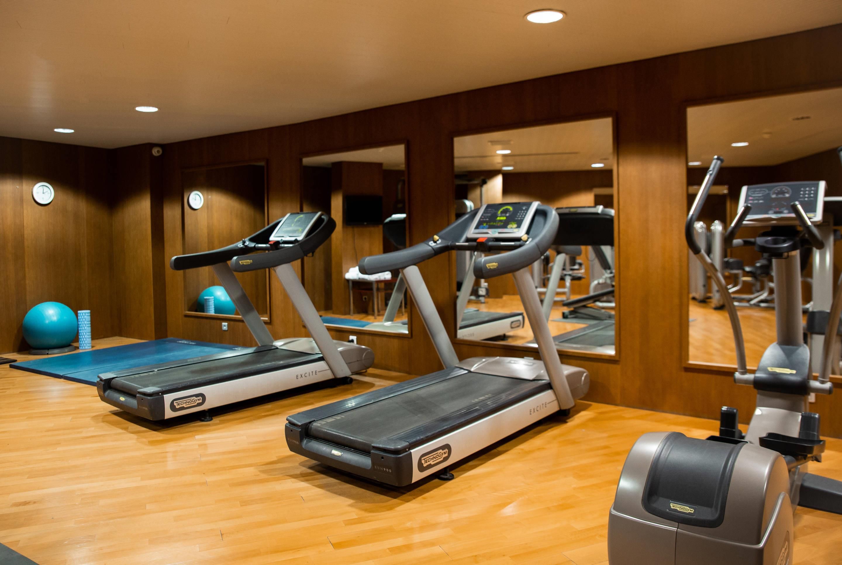 Une salle de sport équipée de tapis de course, de ballons d’exercice et d’un miroir qui reflète l’espace.