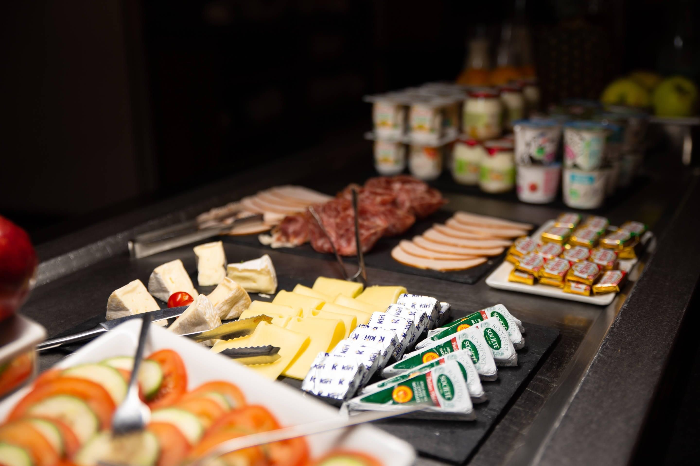 A buffet with various food items including meats, cheeses, and condiments.