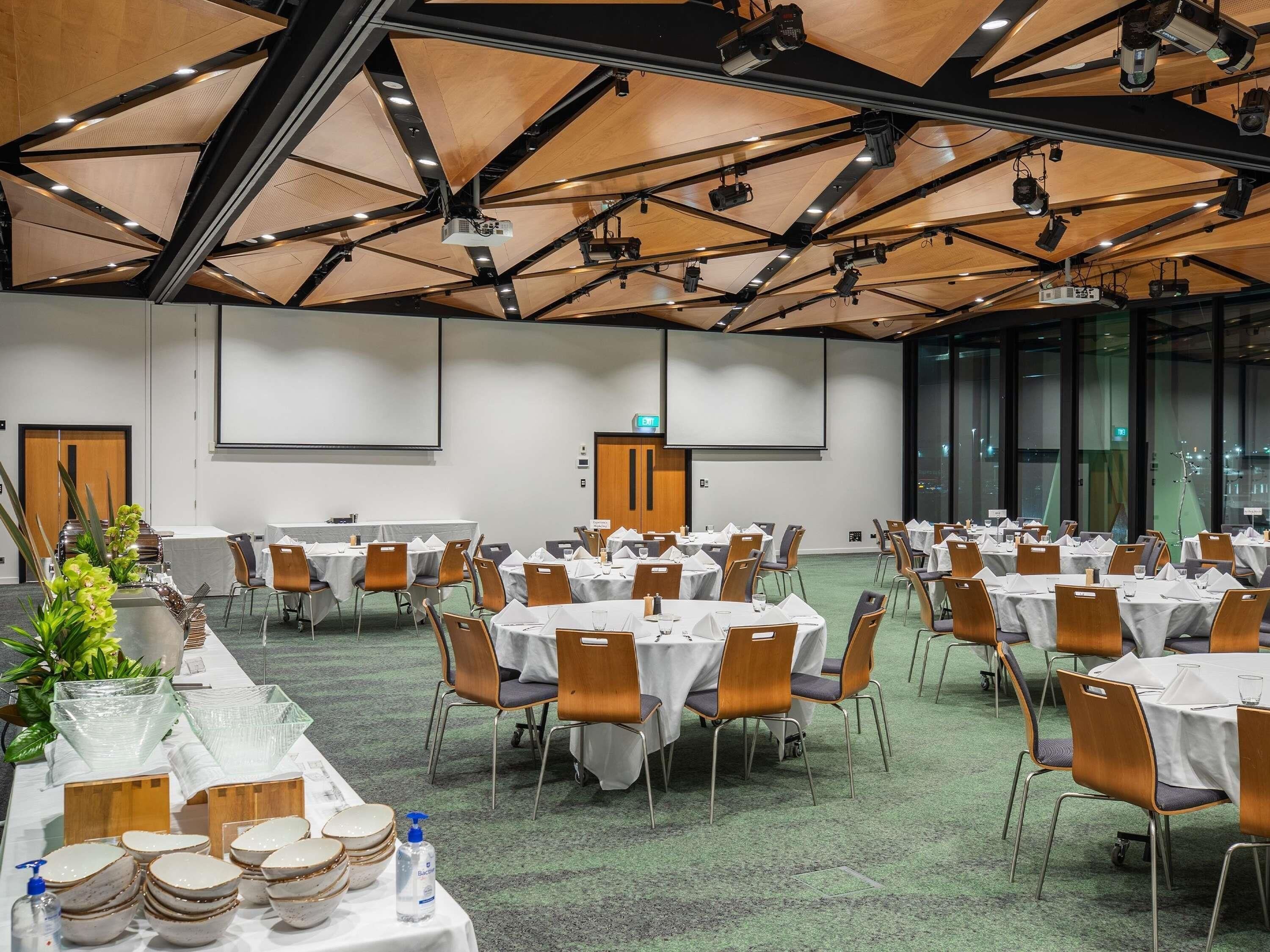 A conference room with round tables, chairs, and a projector screen.